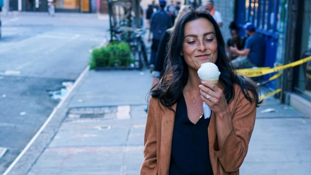 Mujer sujetando helado sonriendo.